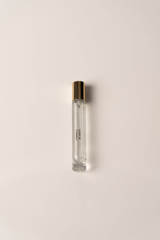 Clear glass perfume bottle with gold cap on a light beige background